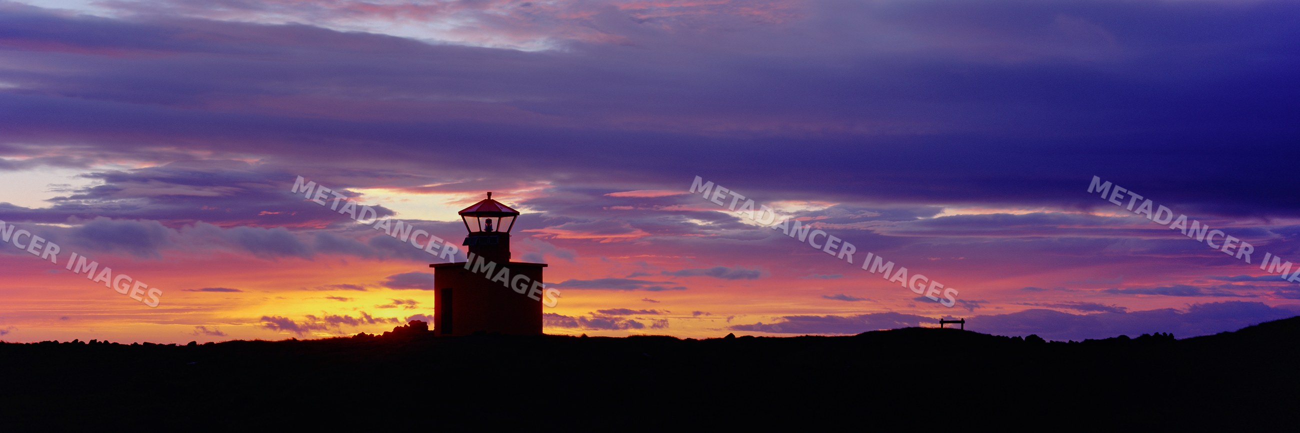 Lighthouse silhouette at colorful sunset over coastal horizon
