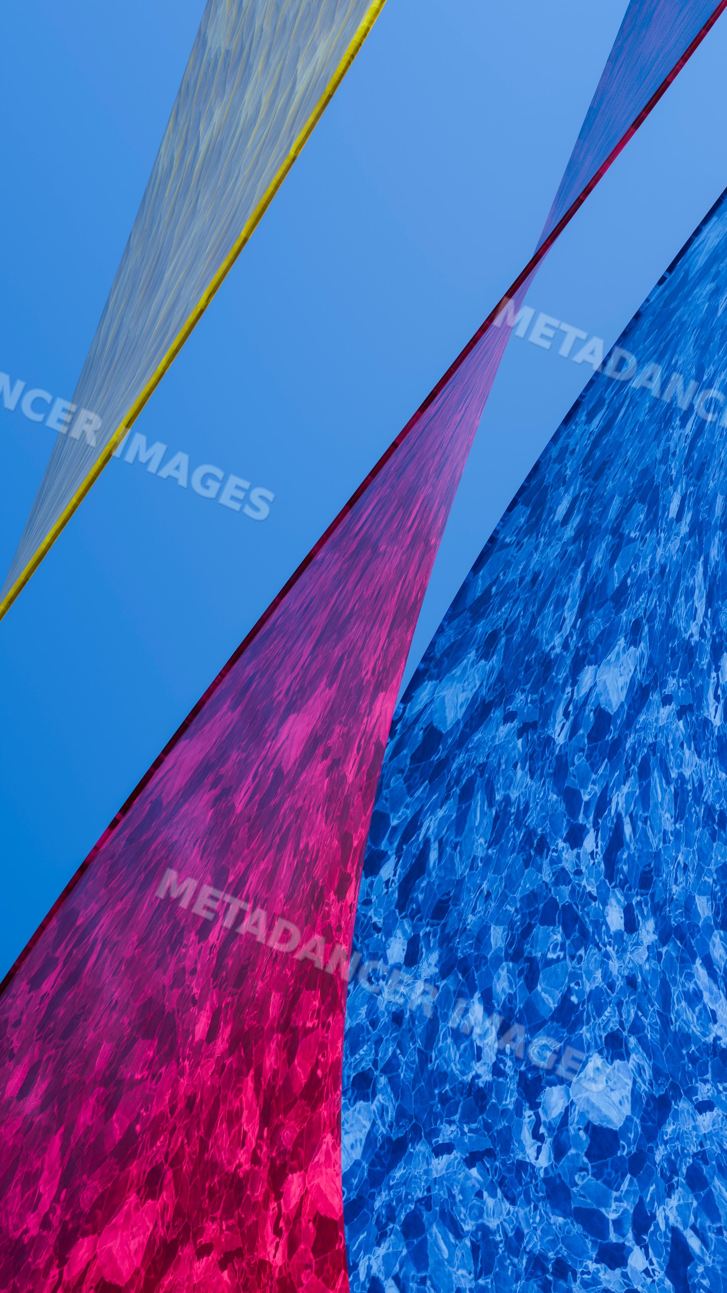 Abstract composition of colored fabric panels against blue sky