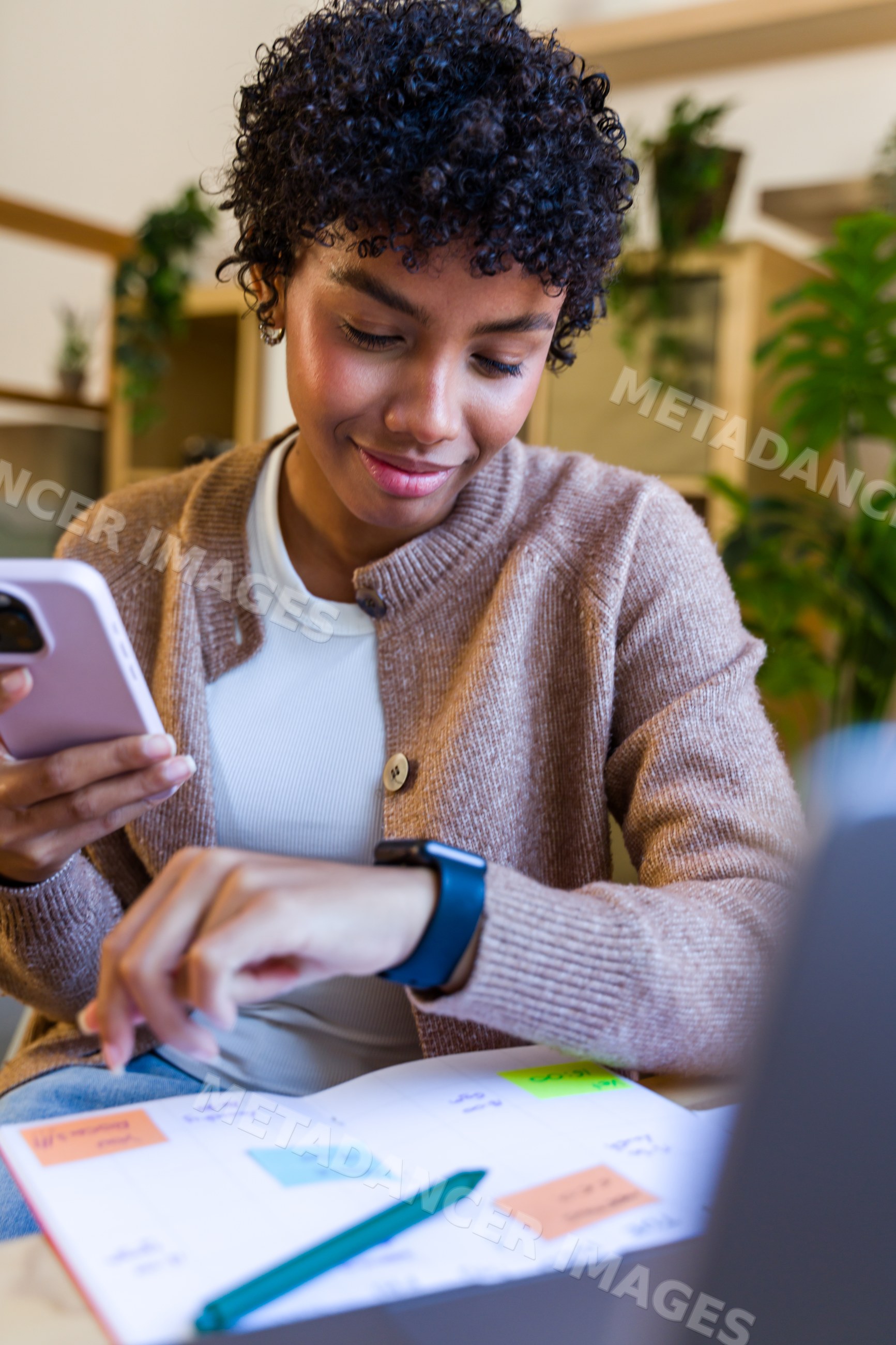 African American woman checking smartwatch and using smartphone