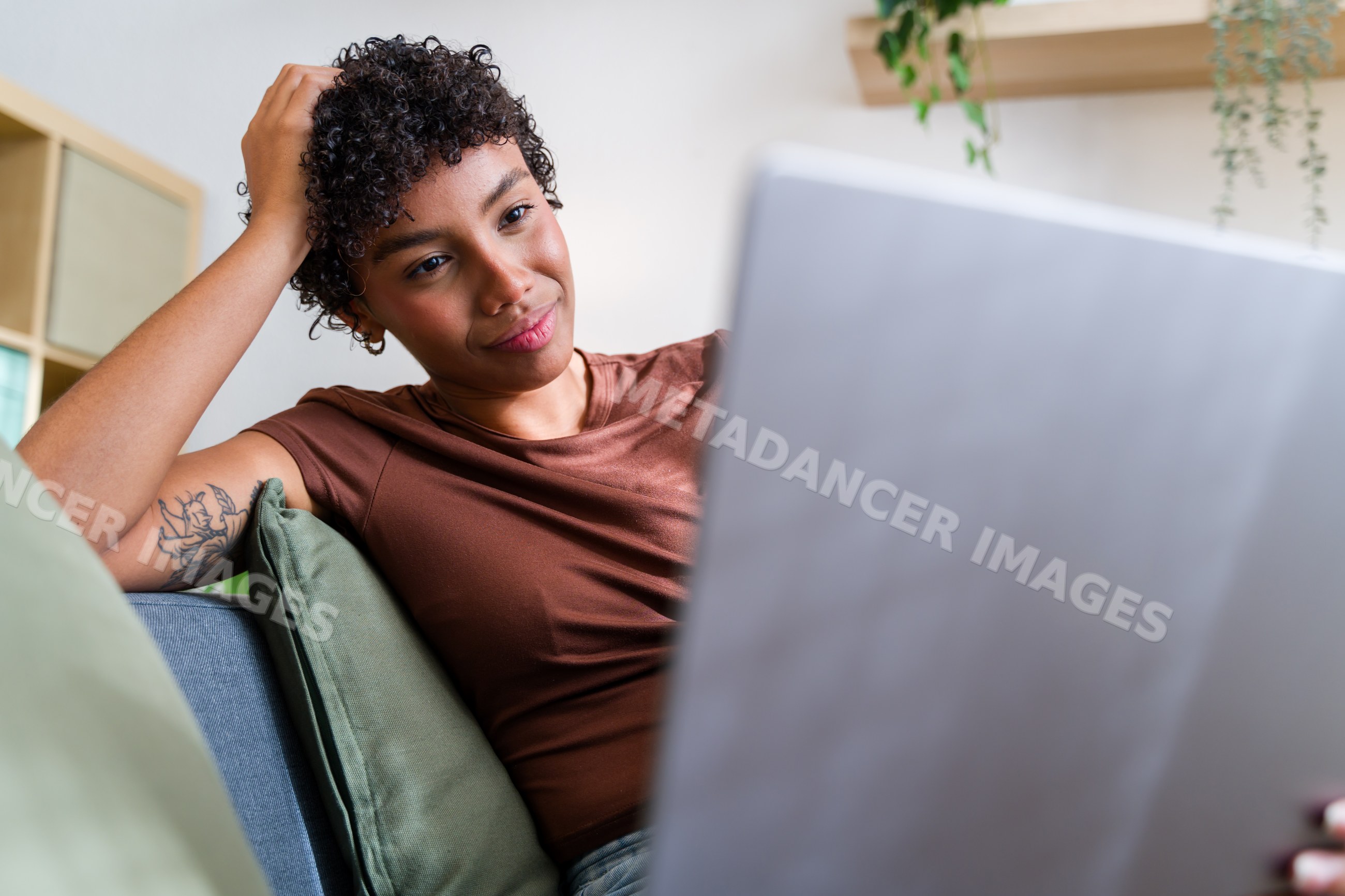 African American woman using laptop sitting on couch with green pillow