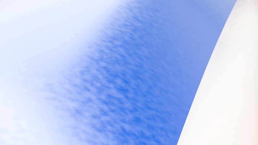White pillar under blue sky with scattered clouds outdoors