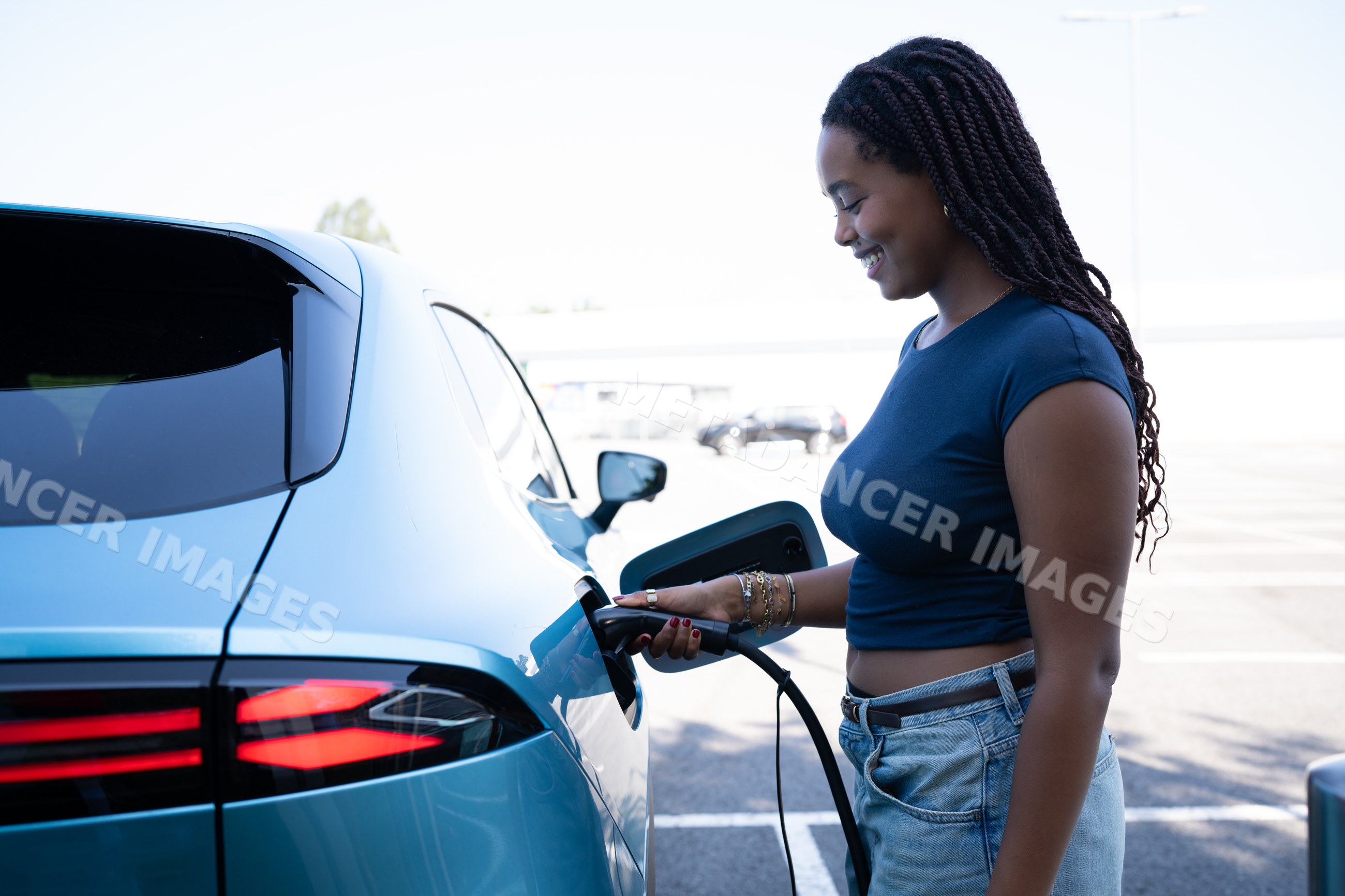 A African American woman charges an electric vehicle