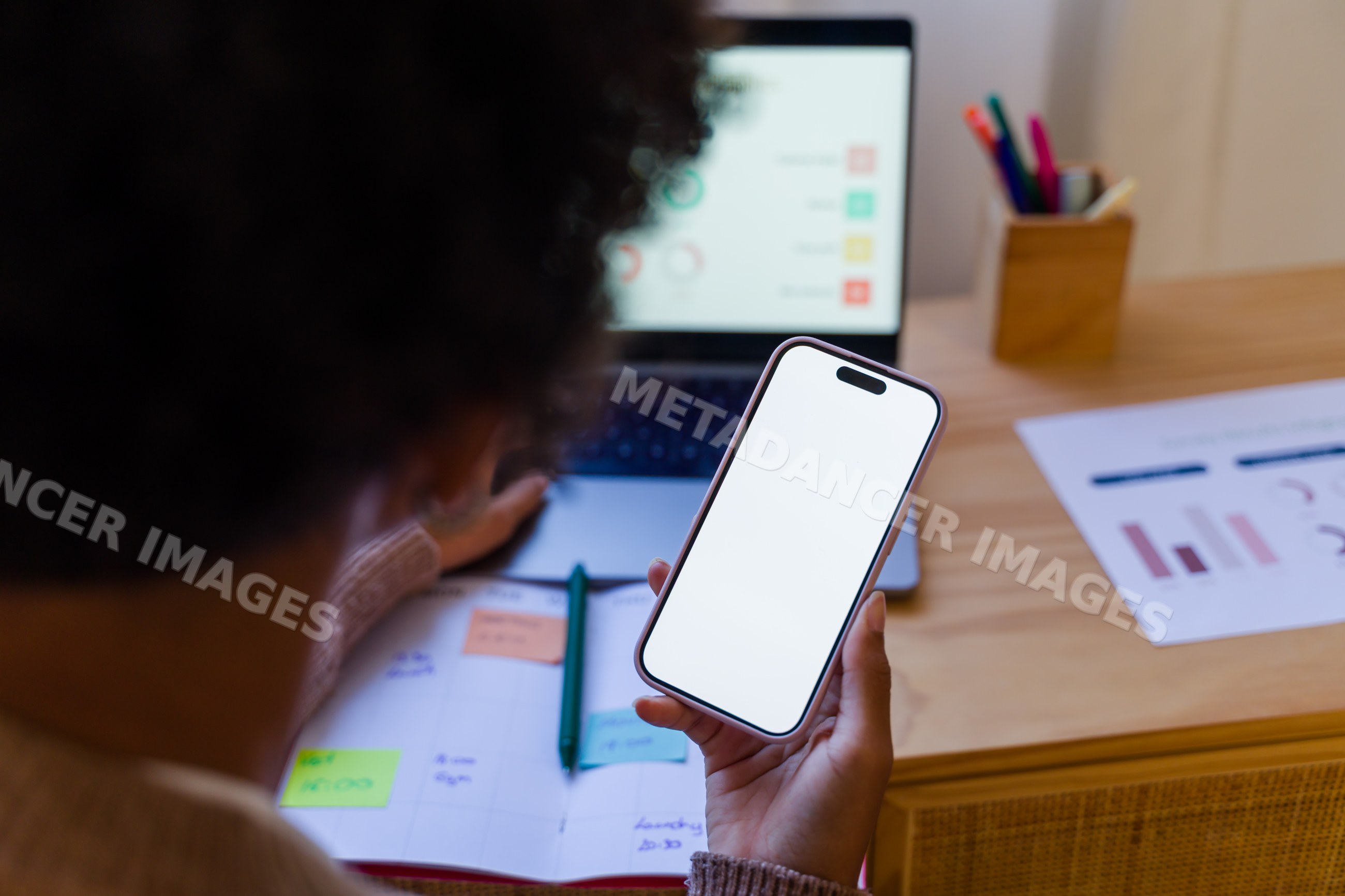 African American person holding mobile phone with blank screen