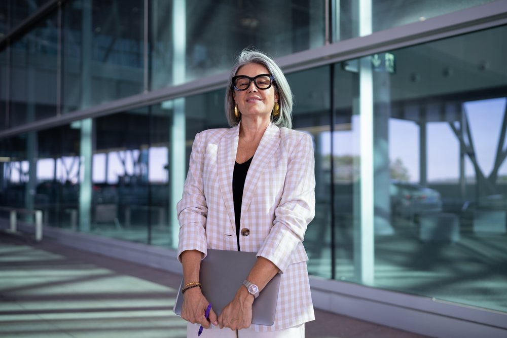 Businesswoman holding laptop outside modern glass building