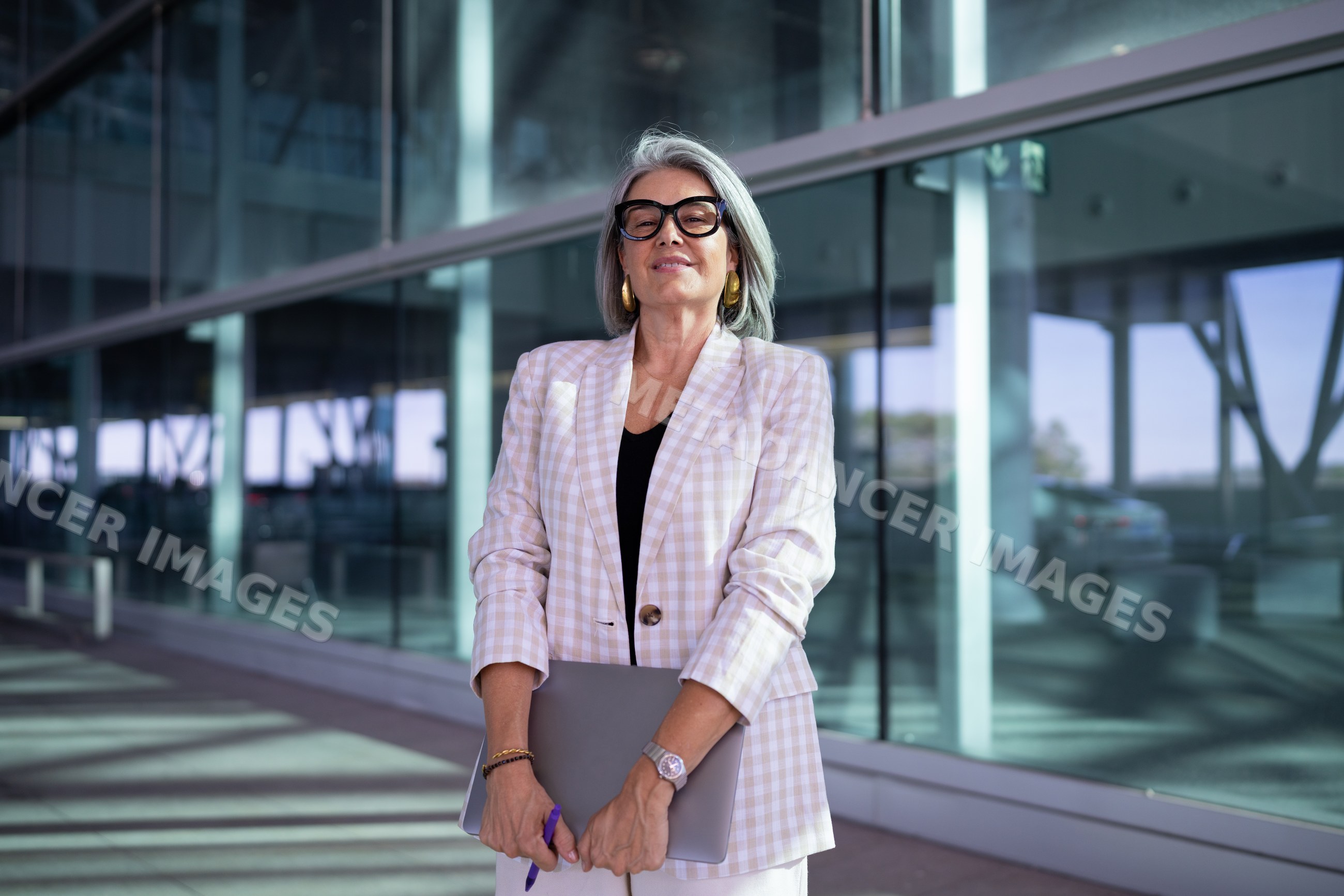 Businesswoman holding laptop outside modern glass building