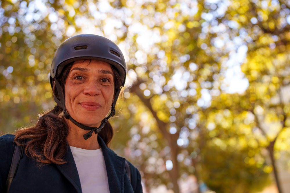 Hispanic woman wearing helmet outdoors with autumn trees
