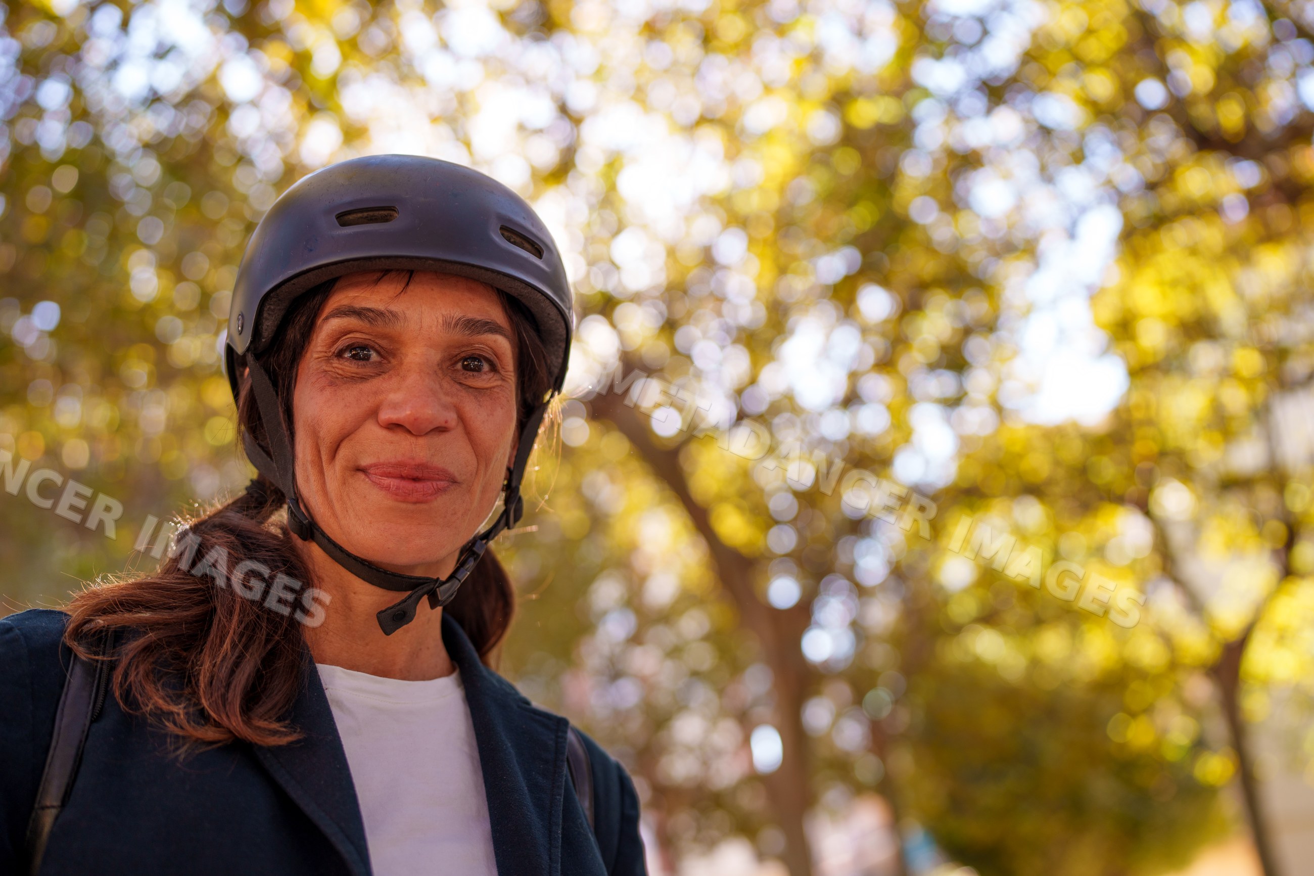 Hispanic woman wearing helmet outdoors with autumn trees