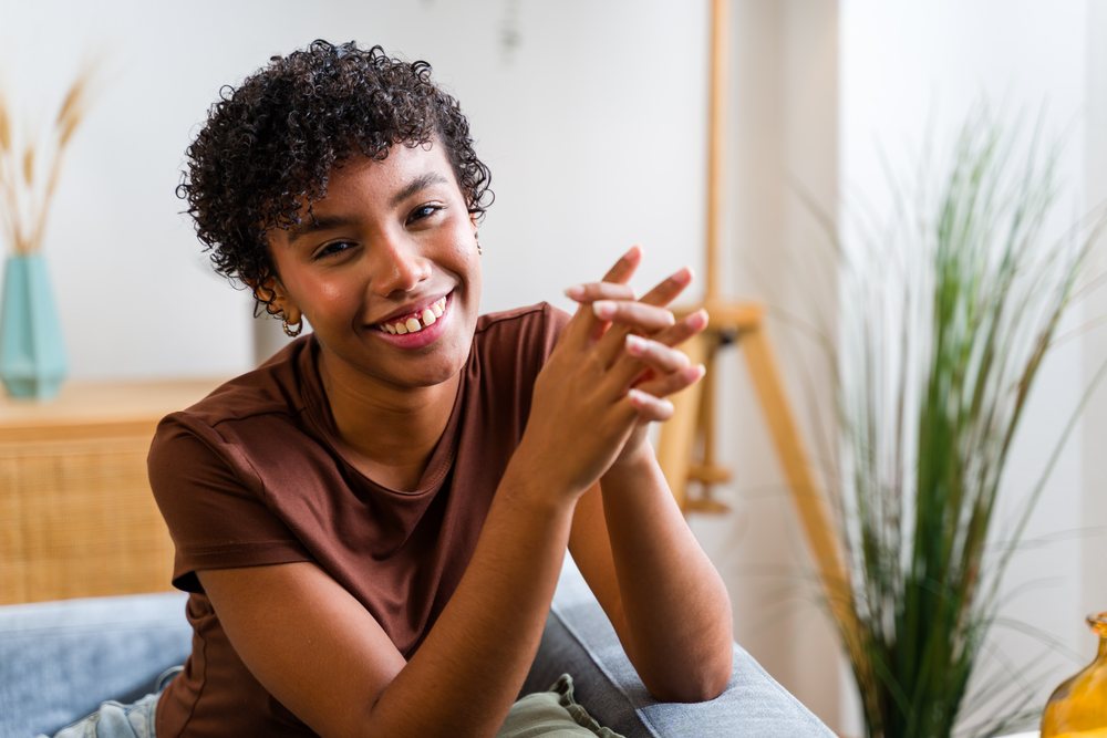 African American woman smiling with curly hair sitting indoors