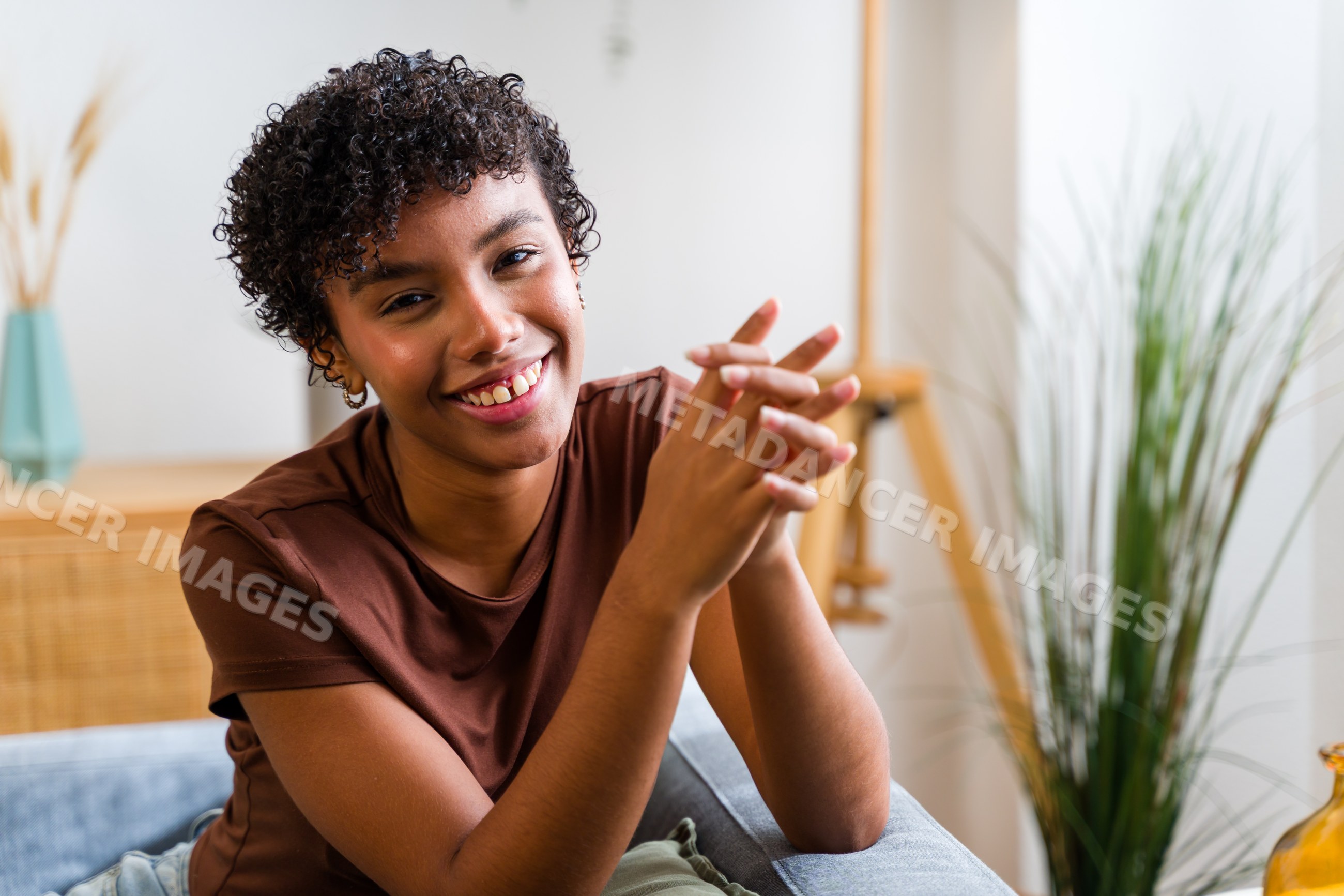 African American woman smiling with curly hair sitting indoors