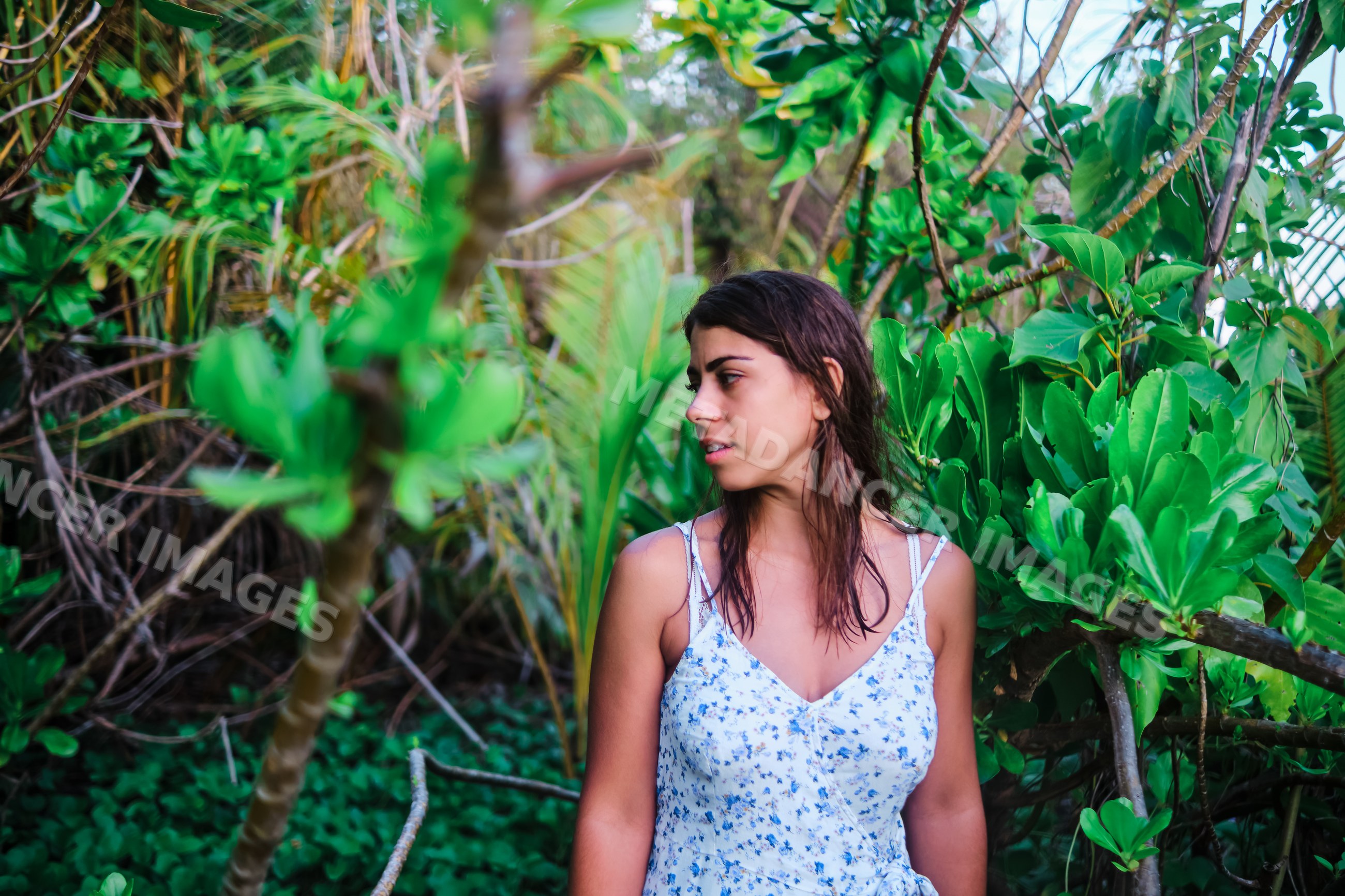 A white woman stands surrounded by tropical greenery
