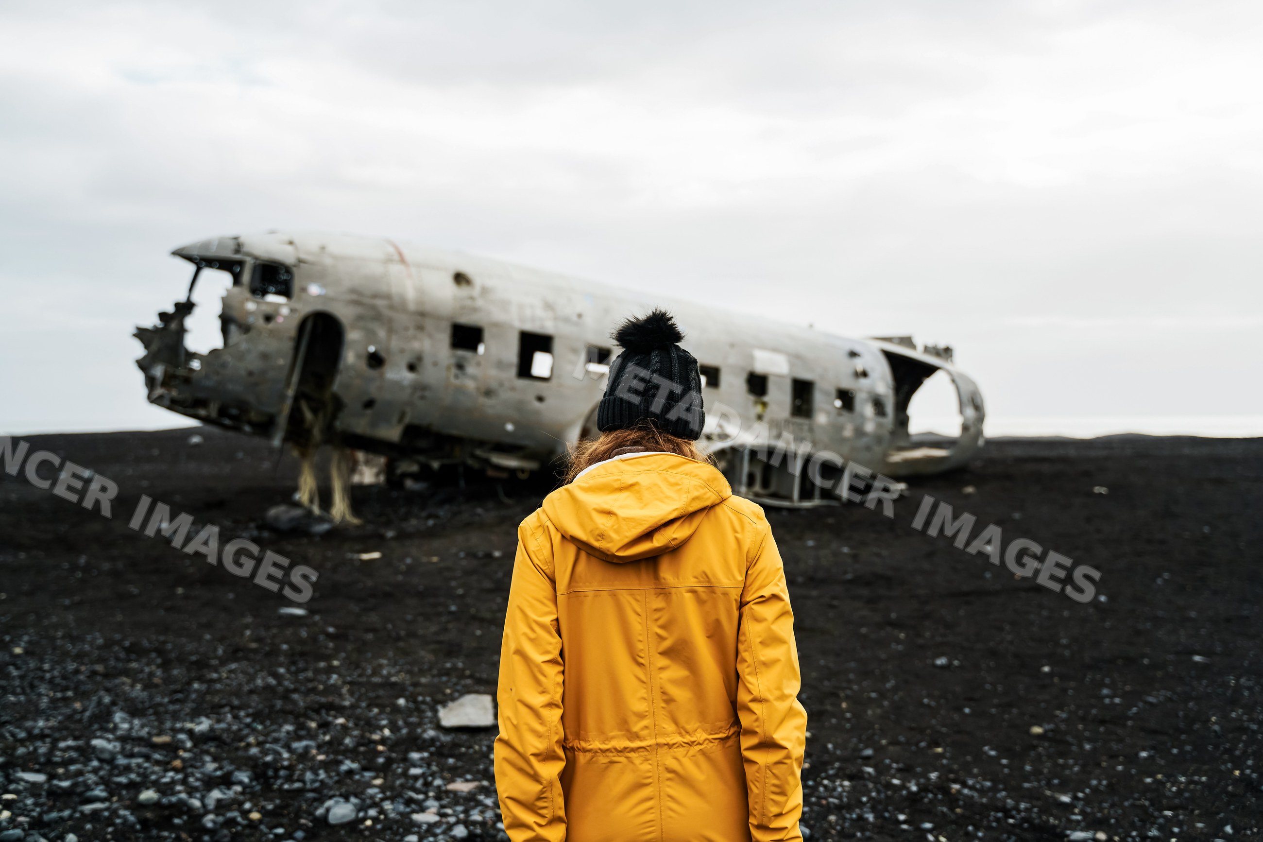 A white woman in a yellow jacket explores a wrecked airplane