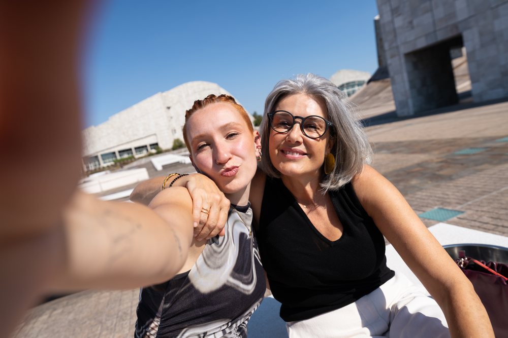 Two white women smiling and taking a selfie outdoors