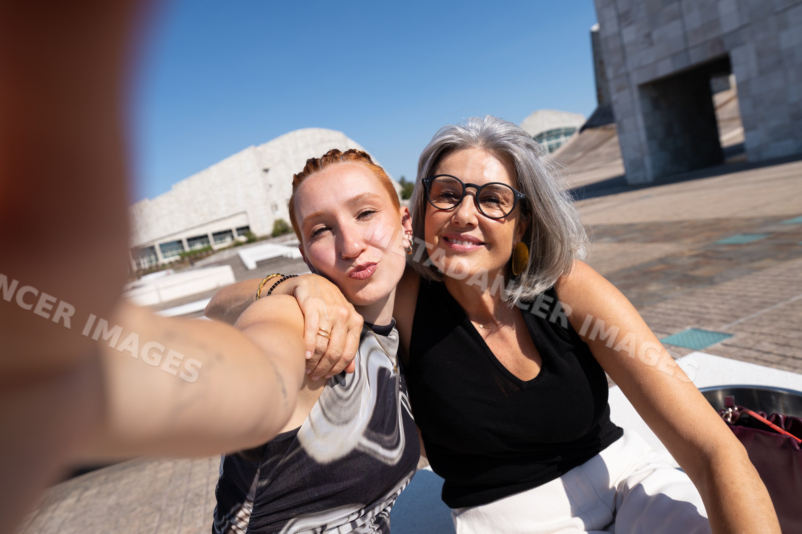 Two white women smiling and taking a selfie outdoors
