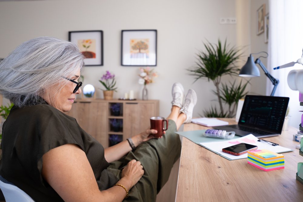 White woman relaxing at desk with coffee cup in home office setup