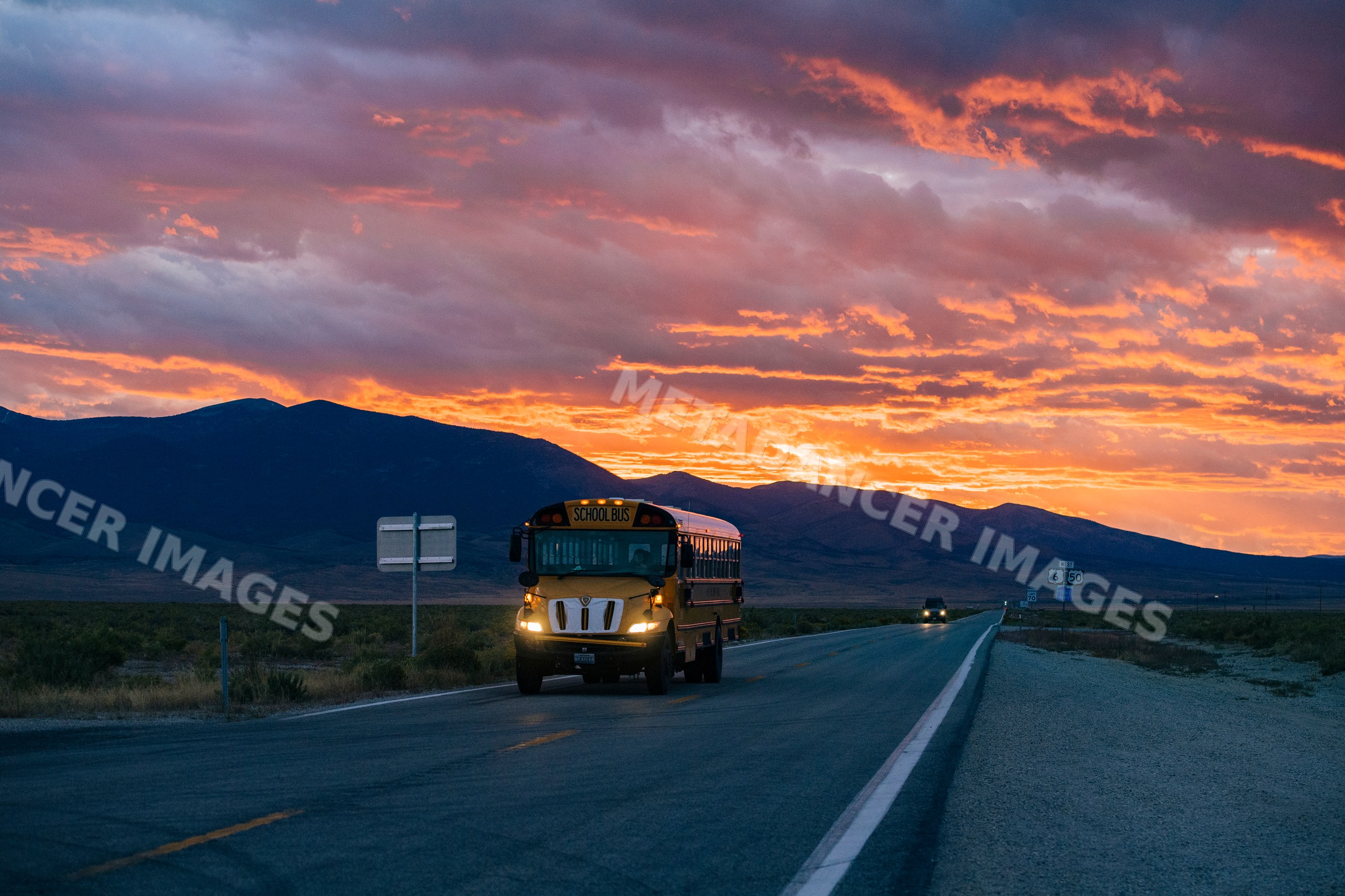 School bus driving on highway at sunset in Nevada