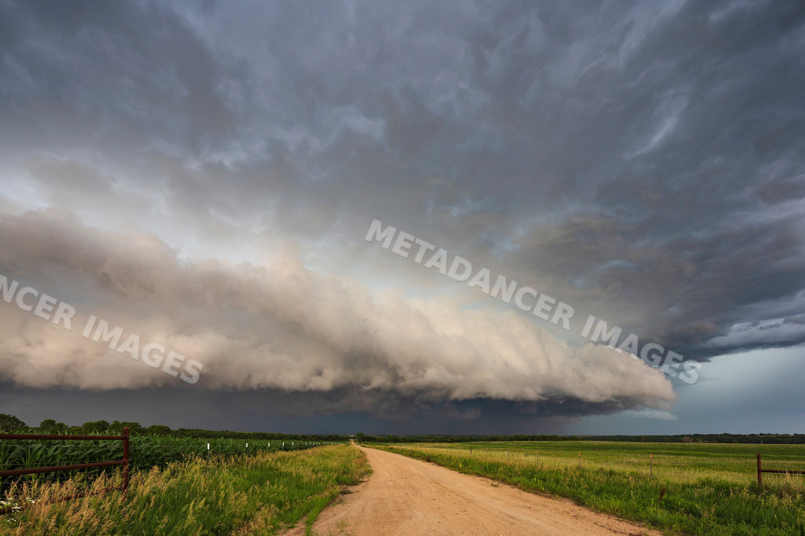 Supercell storm clouds over rural kansas dirt road