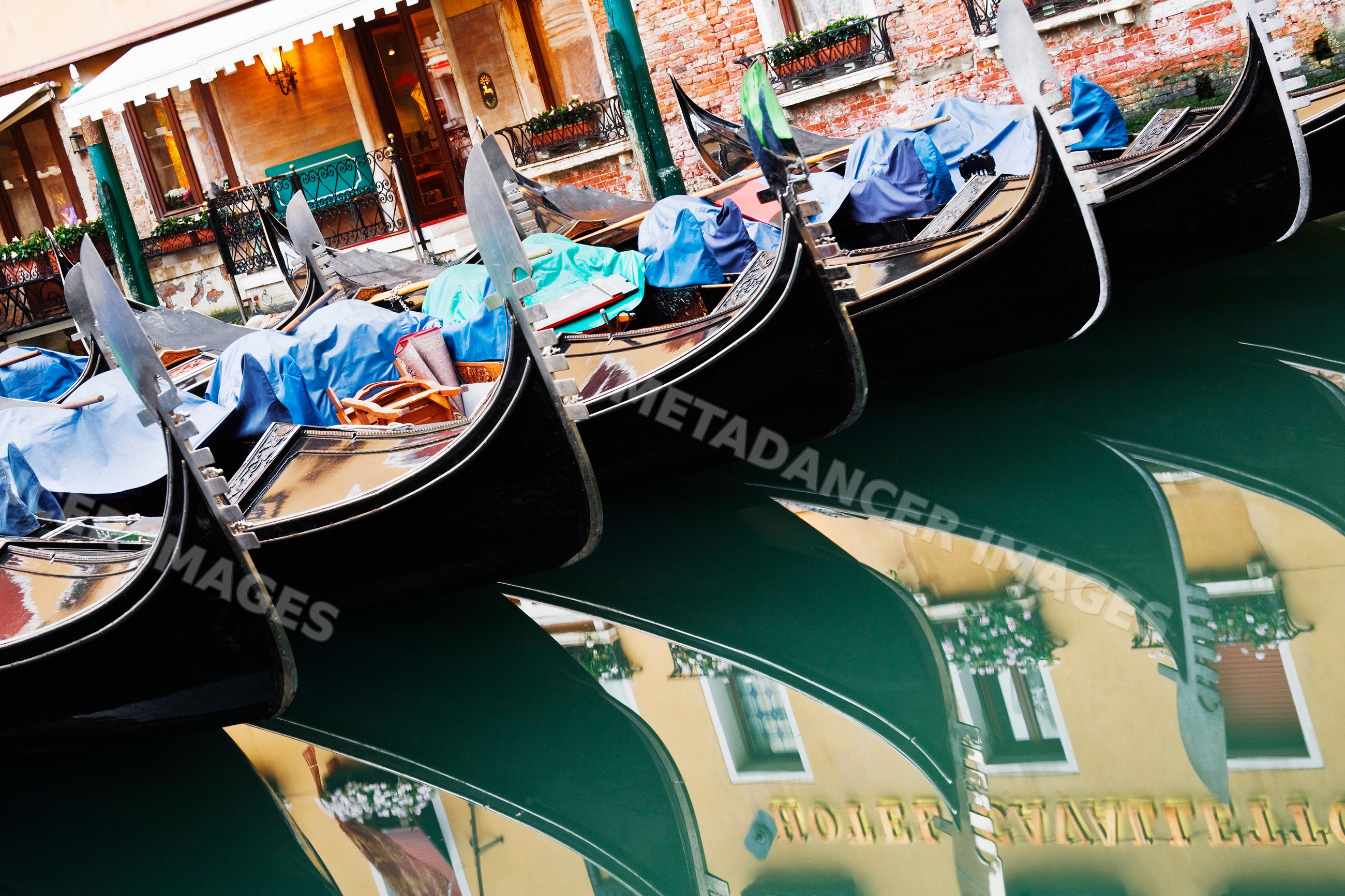 Row of six gondolas docked in a venetian canal, italy