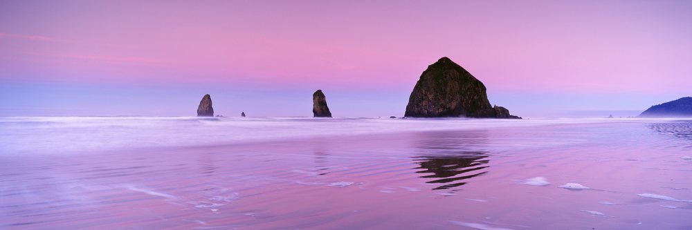 Haystack rock and ocean waves at sunset