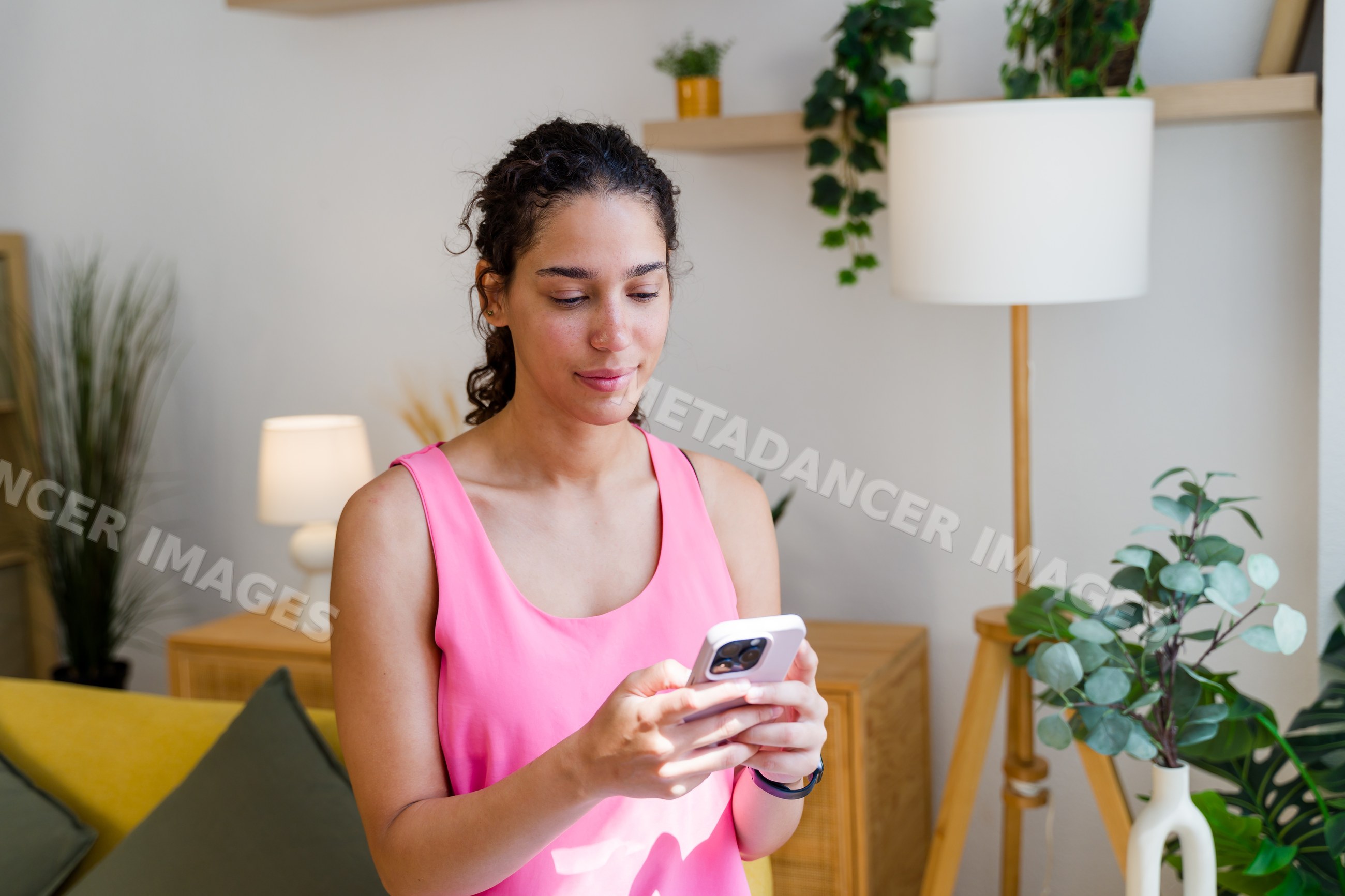 A Hispanic woman uses her smartphone in a cozy living room