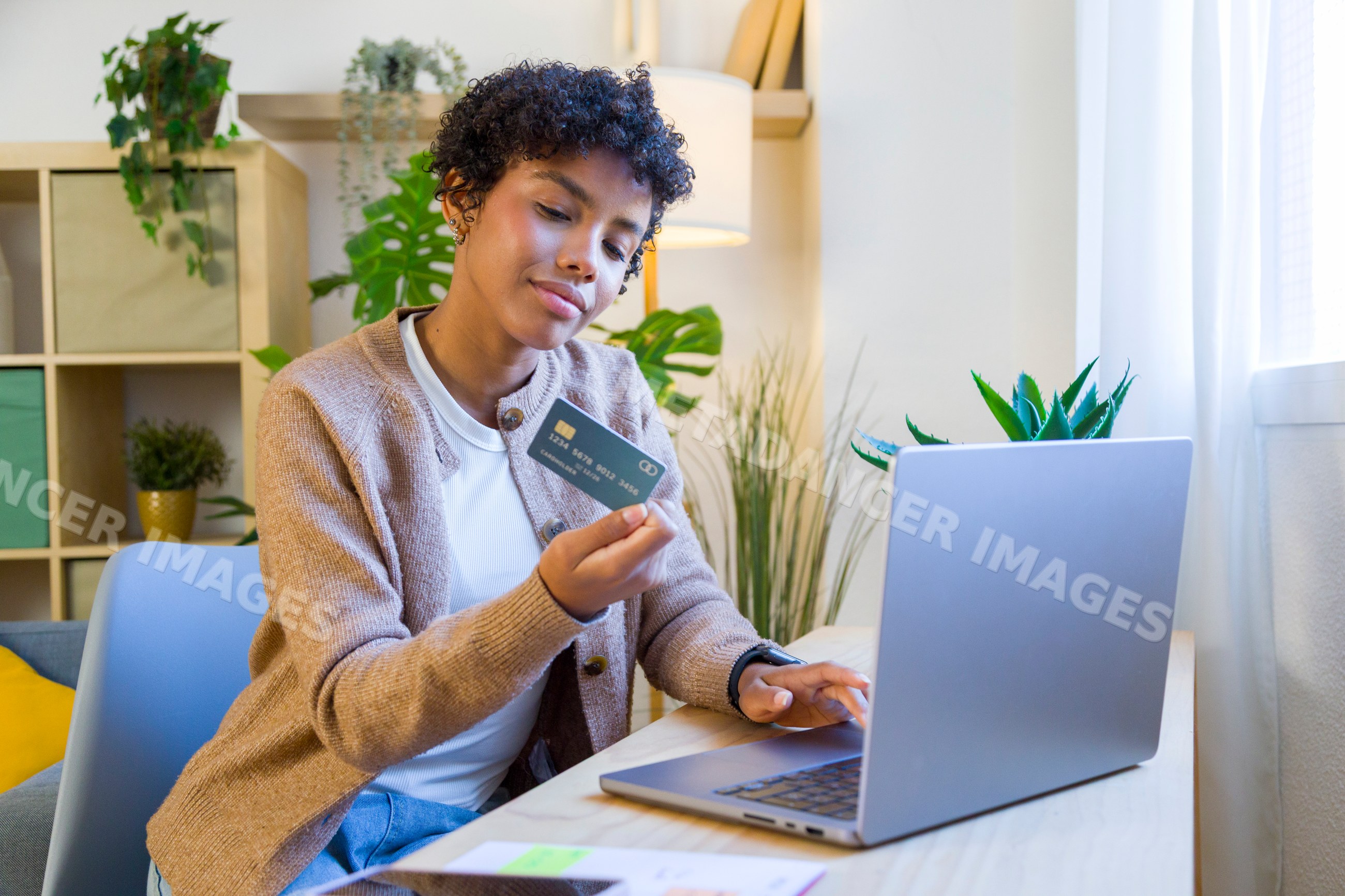 African American woman using credit card and laptop in home office