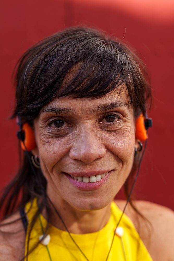 Hispanic woman smiling with orange headphones against a red background