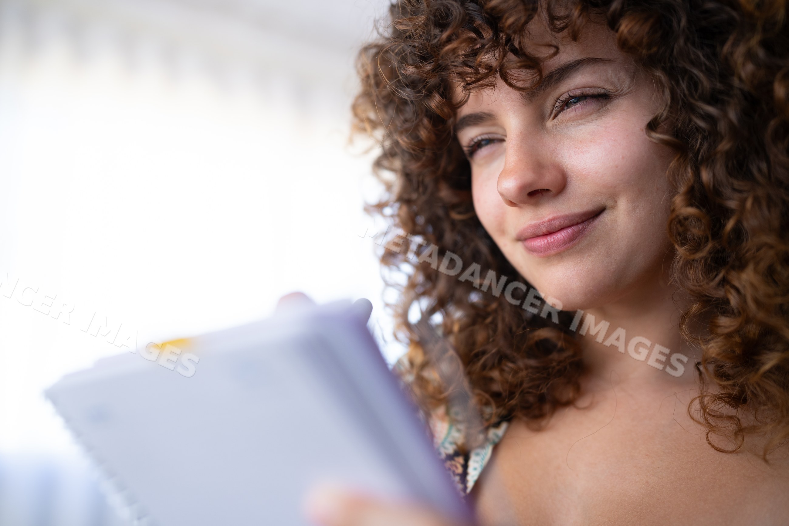 White woman smiling while holding spiral notebook indoors