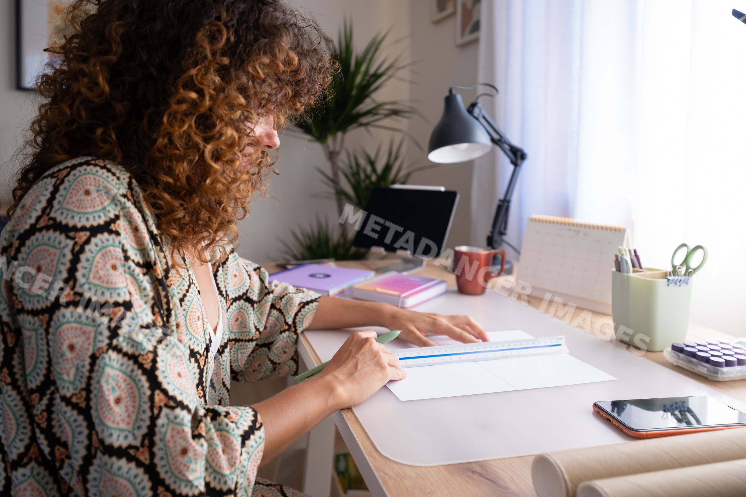 White woman measuring paper with ruler in cozy home office workspace