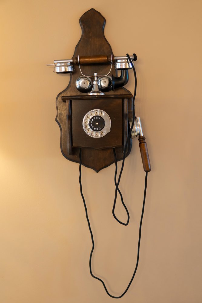 Retro wooden rotary dial telephone with metal bells mounted on wall