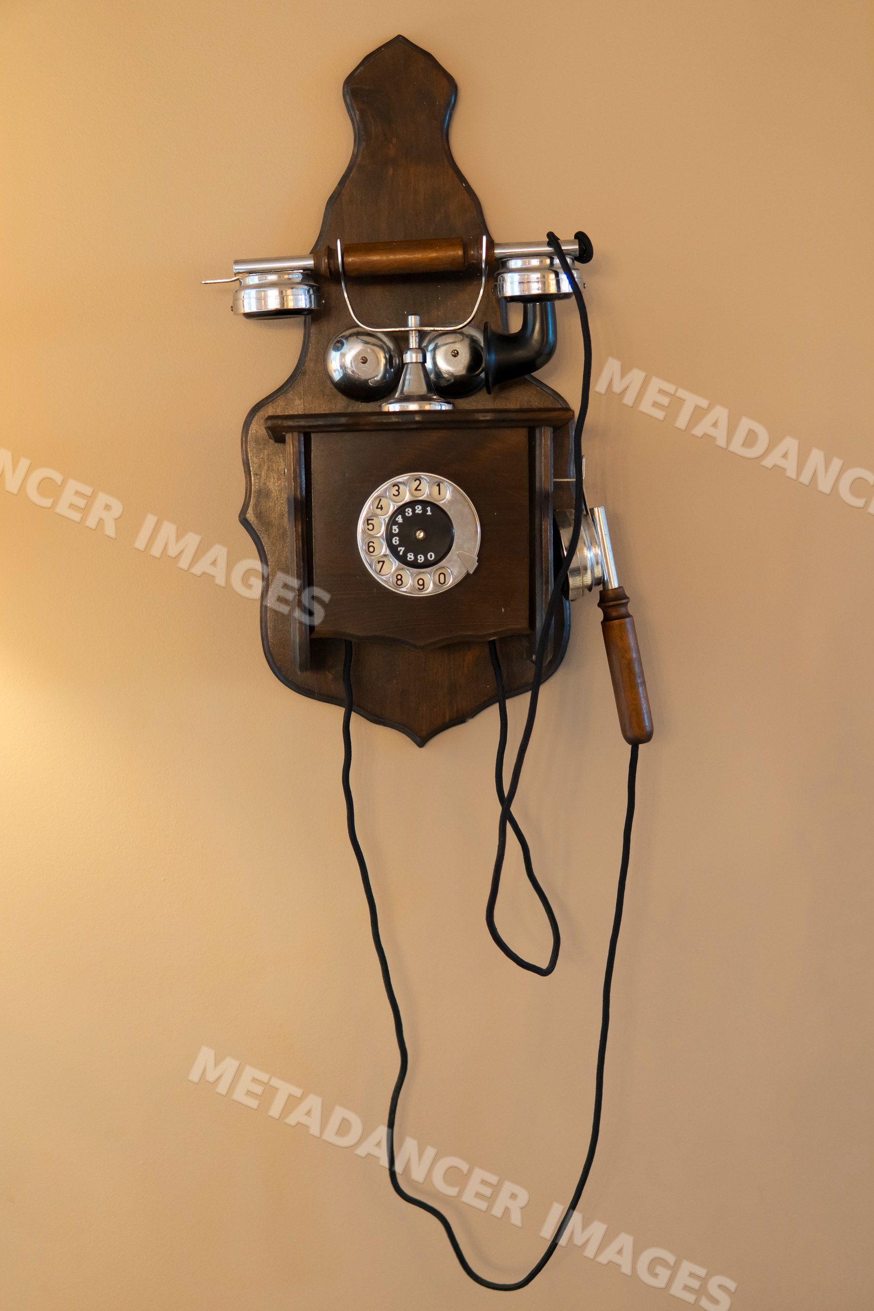 Retro wooden rotary dial telephone with metal bells mounted on wall