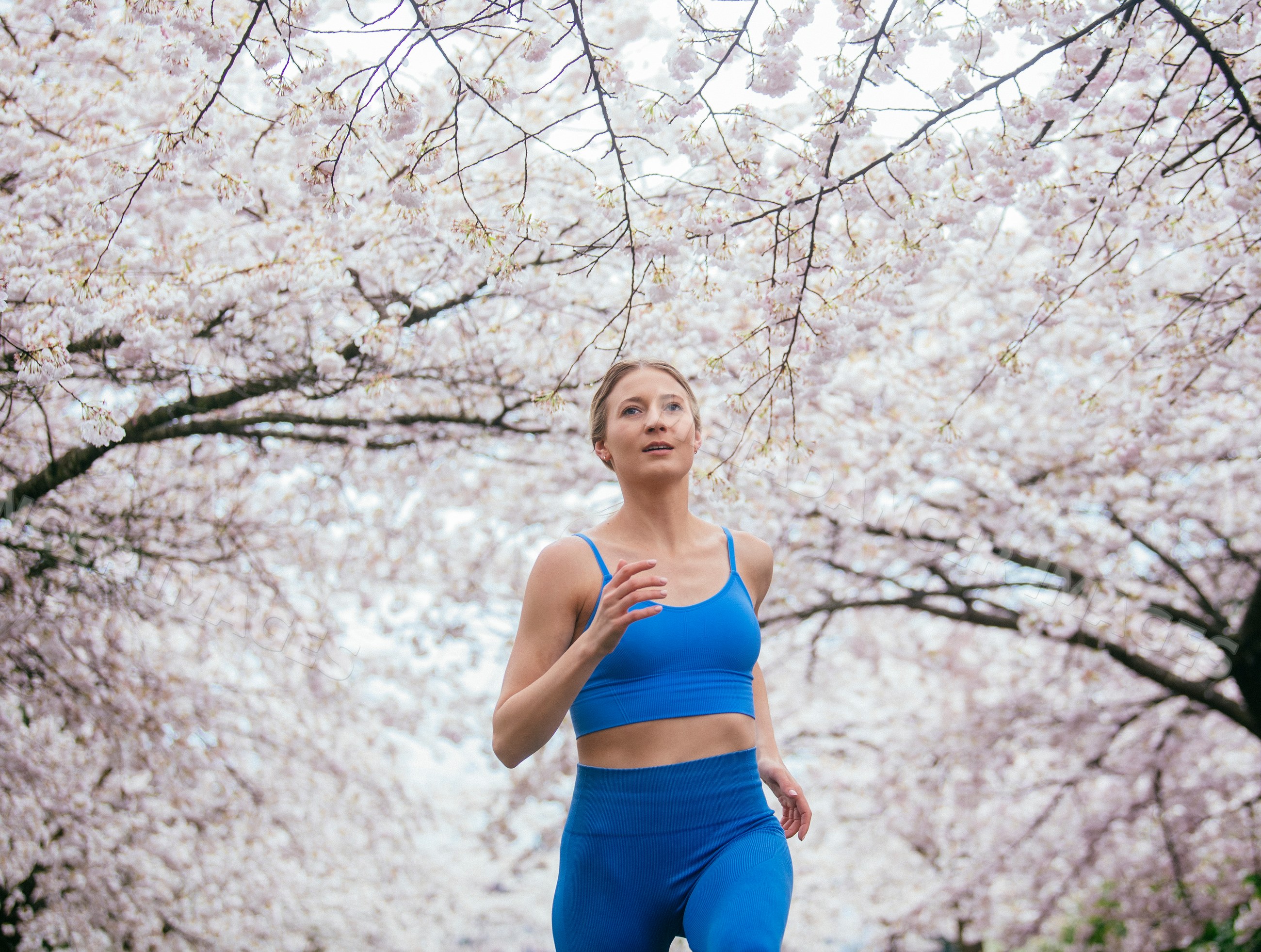 White woman running outdoors in blooming cherry blossoms in USA spring