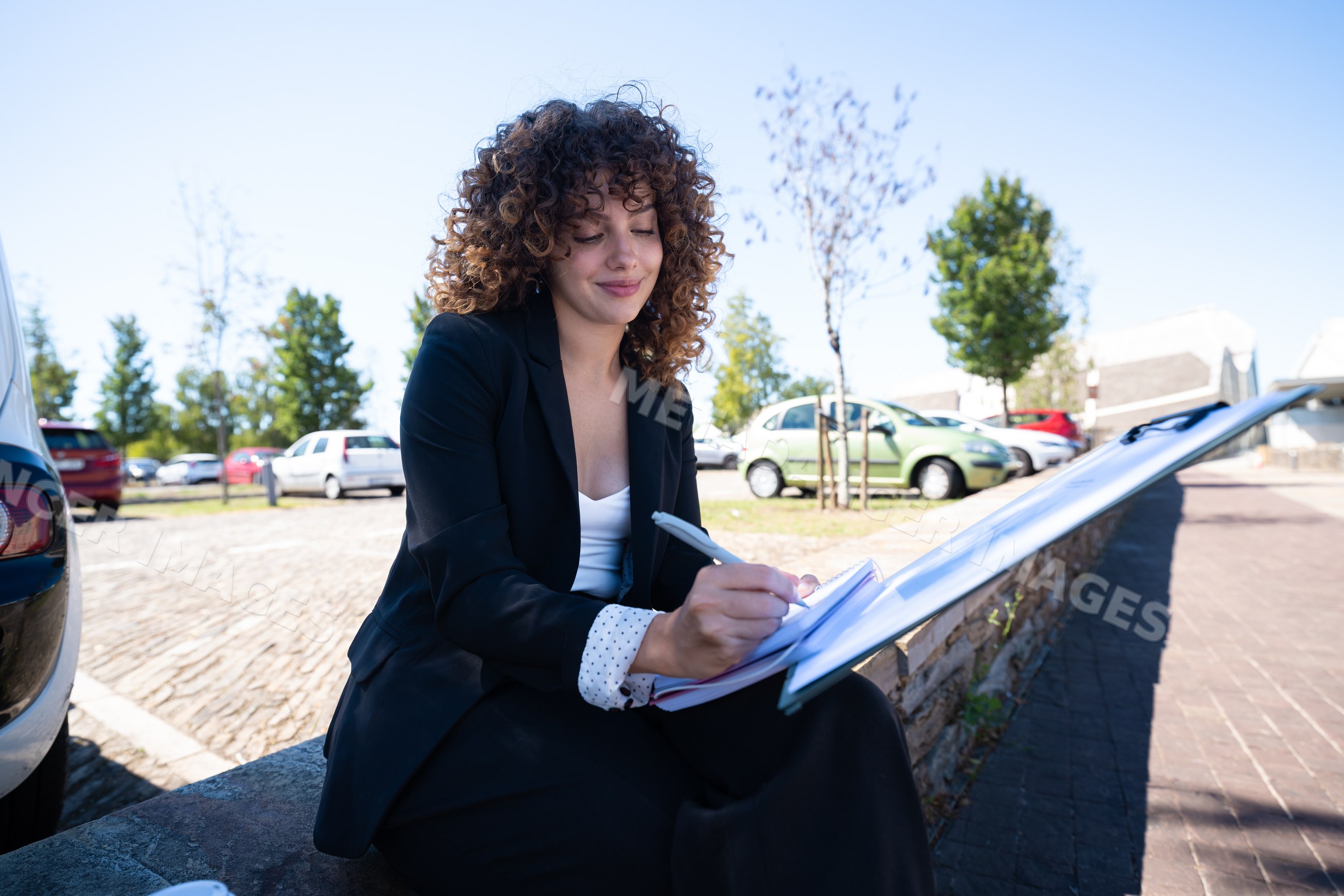 Businesswoman writing notes outdoors in urban car park in a park