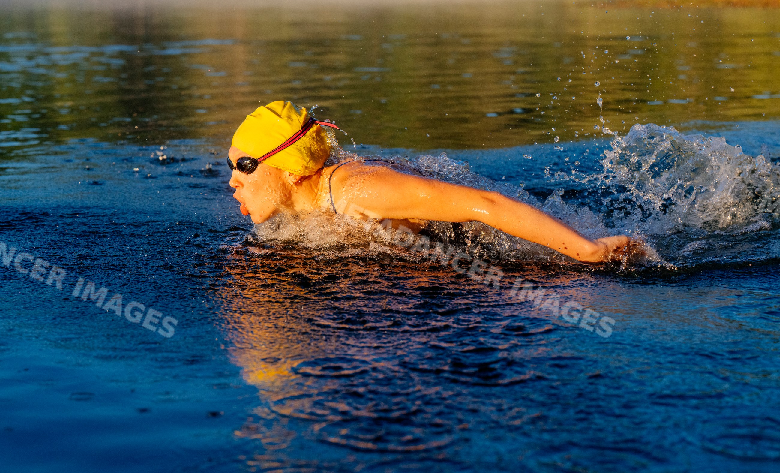 White swimmer wearing yellow swim cap swimming breaststroke