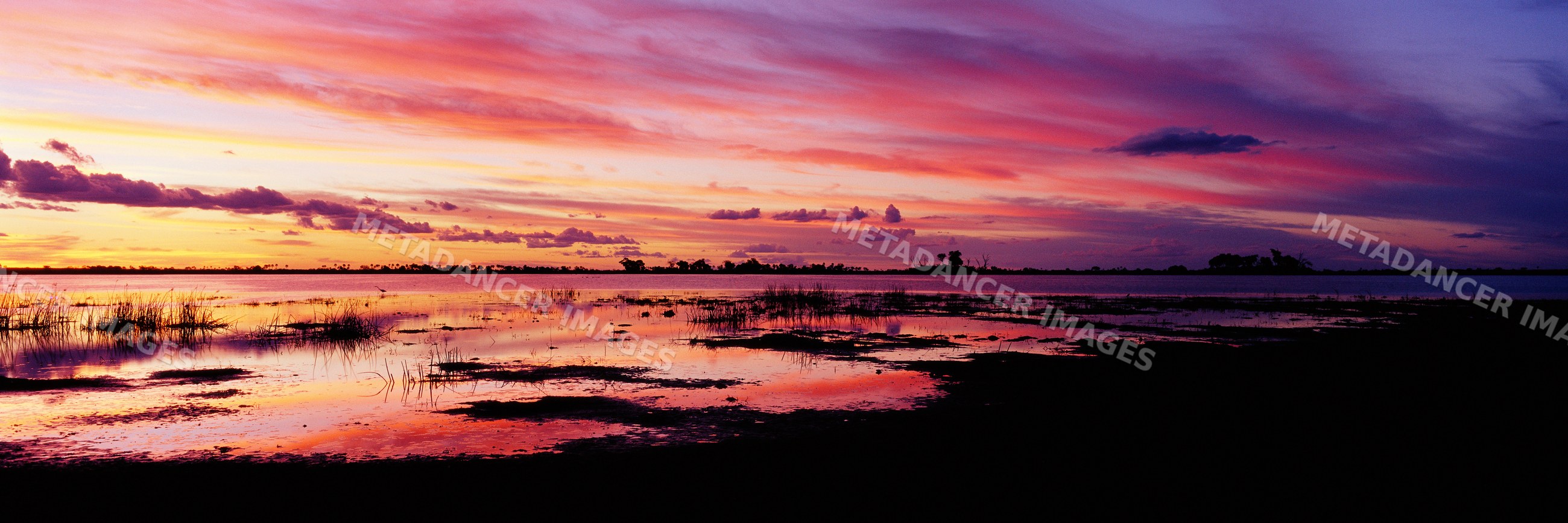 Sunset over lagoon with vivid cloud reflections and tranquil water