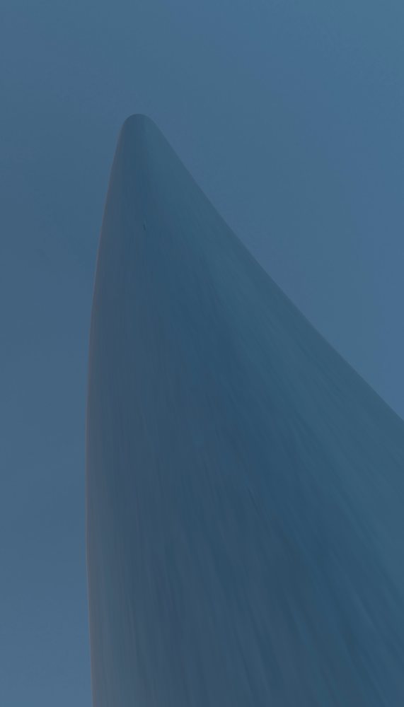 Low angle view of a smooth, pointed monument structure against blue