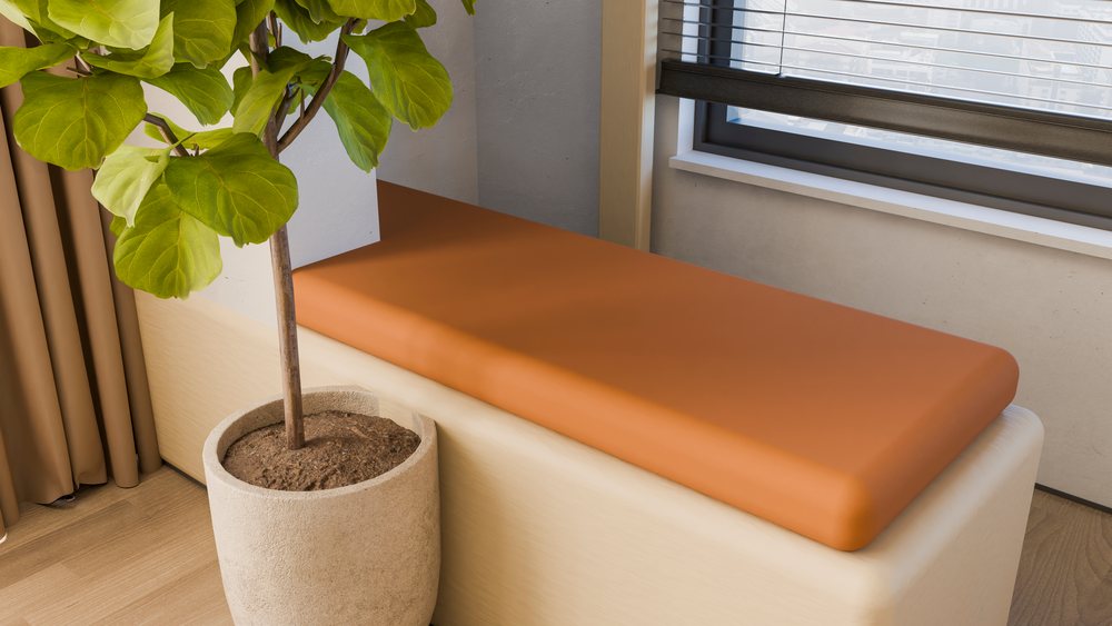 Bench with orange cushion beside potted plant under window blinds
