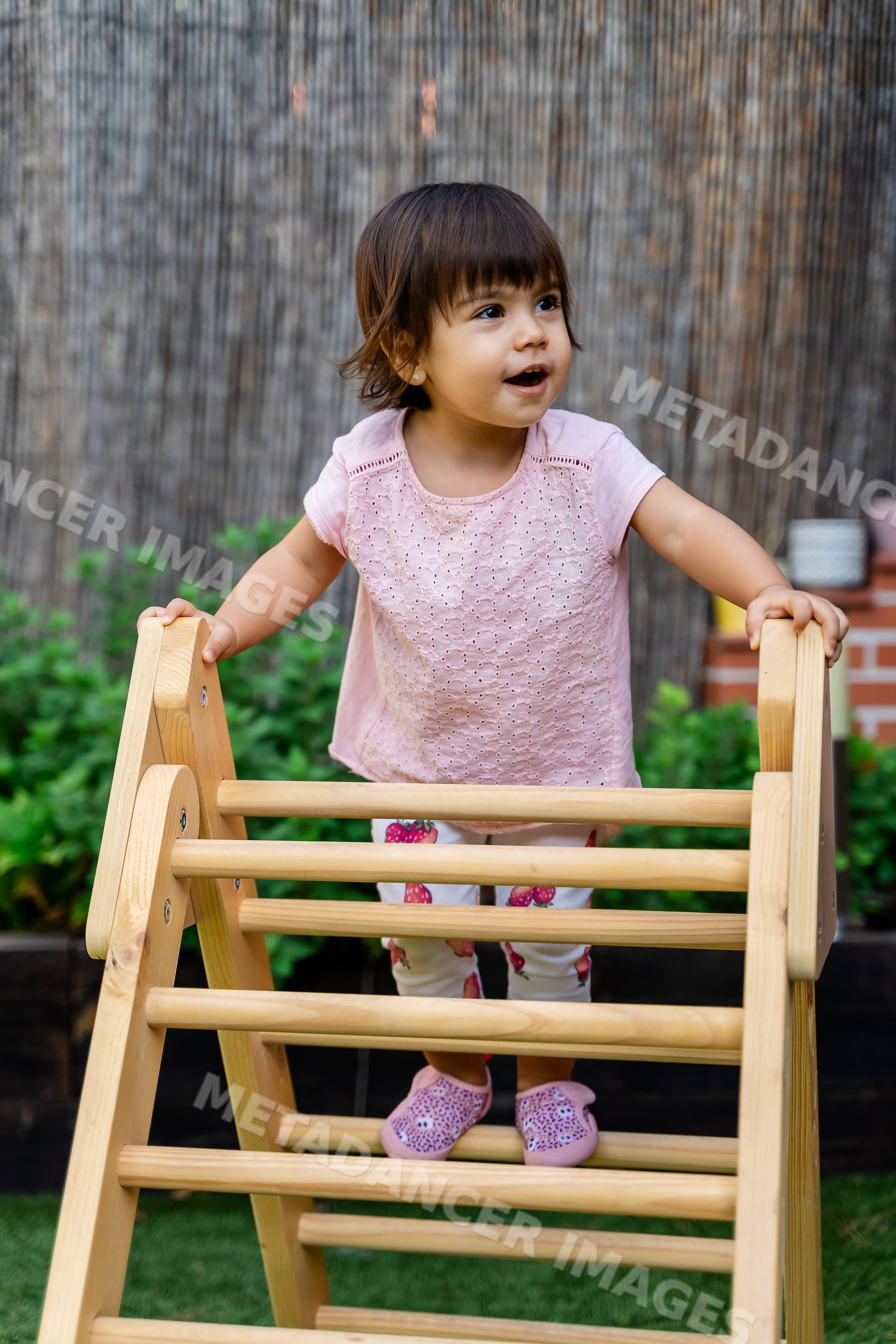 Toddler climbing wooden play structure outdoors in a garden in Spain