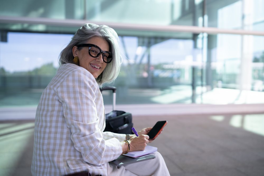 Businesswoman smiling with smartphone and notebook