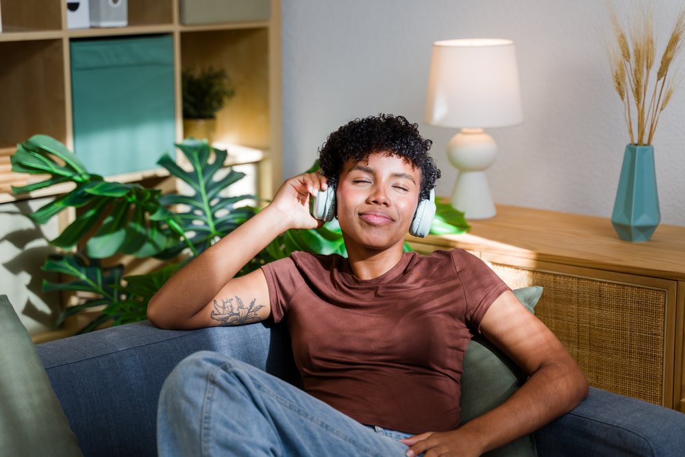 African American woman relaxing with wireless headphones on sofa