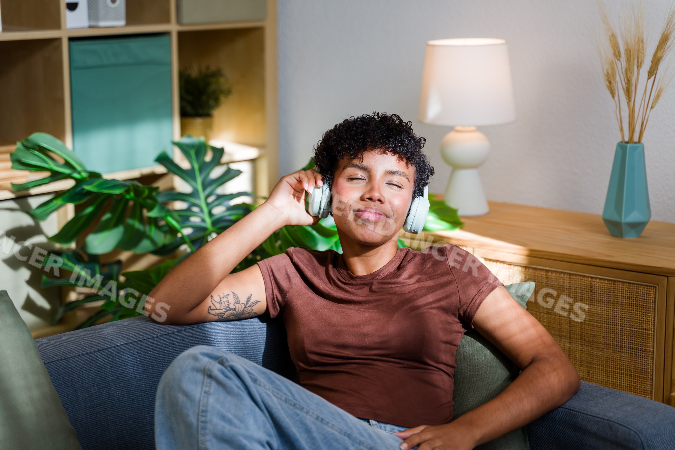 African American woman relaxing with wireless headphones on sofa
