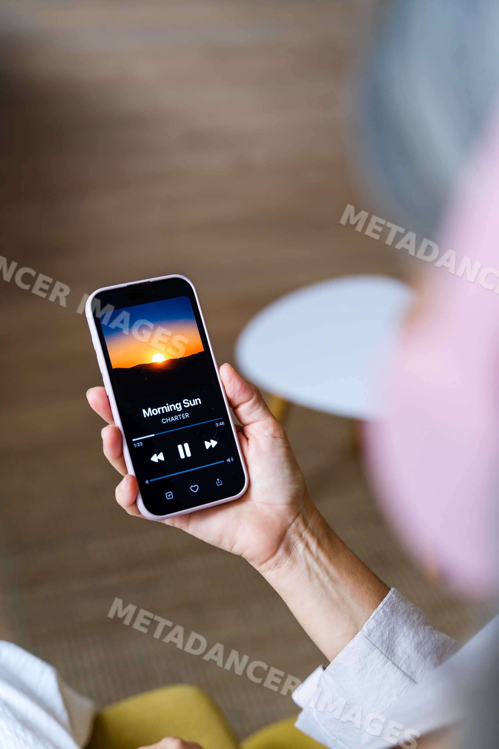 White person holding smartphone with music player paused on 'morning