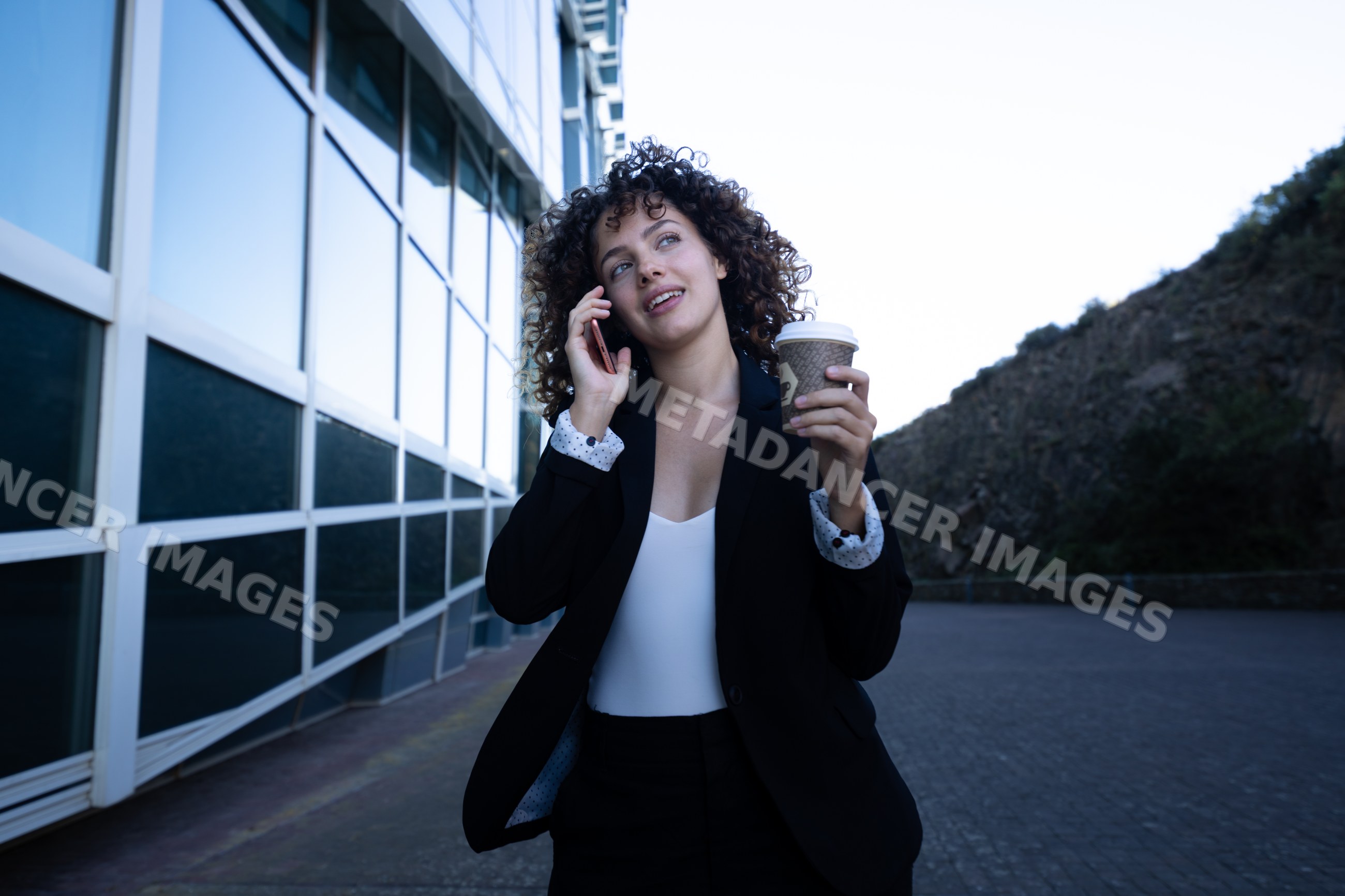 Businesswoman holding coffee cup and talking on phone