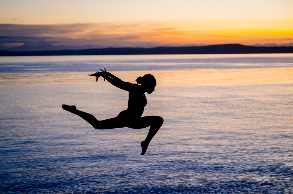 Hispanic woman performing yoga acrobatic jump