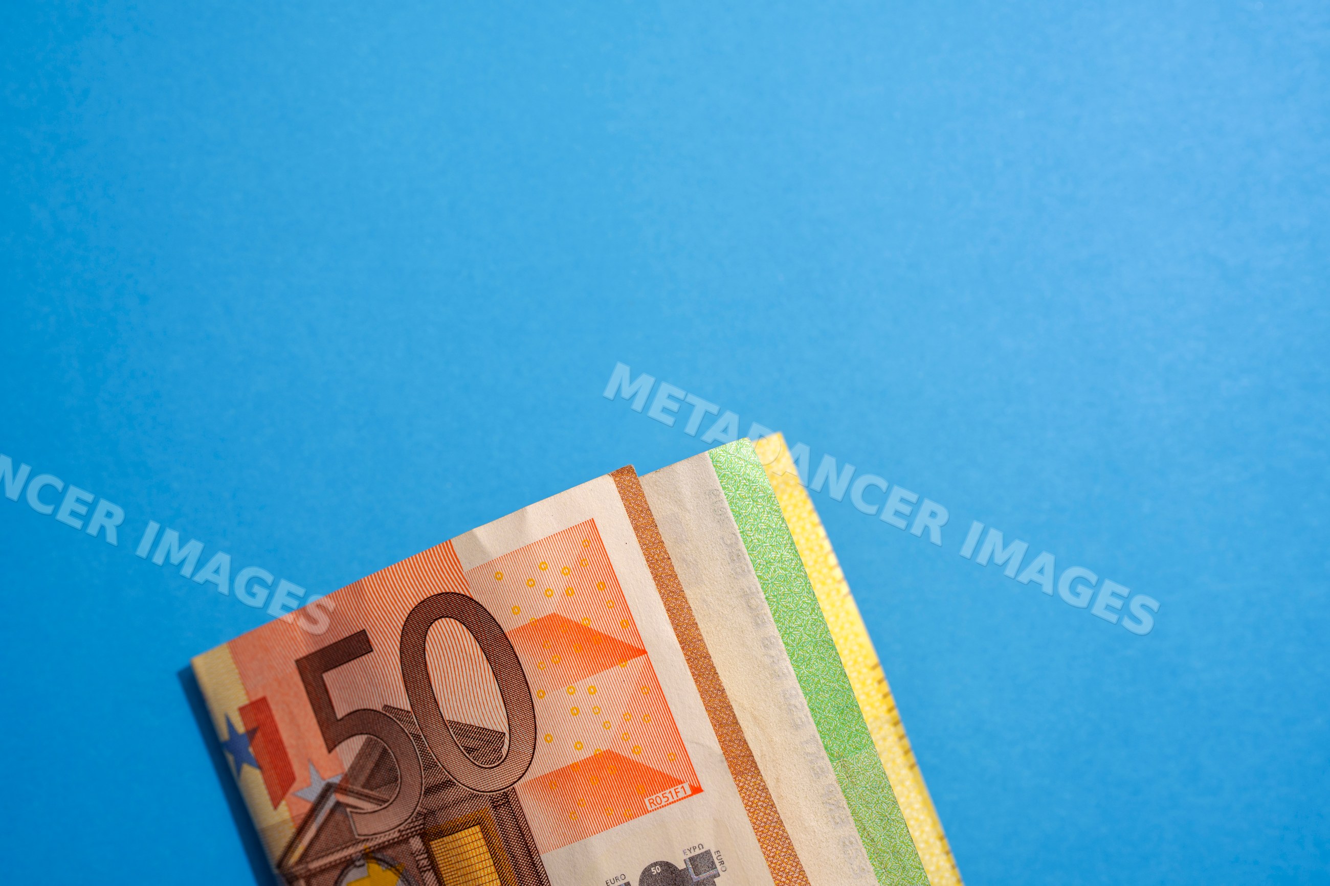Folded euro banknotes against blue studio background