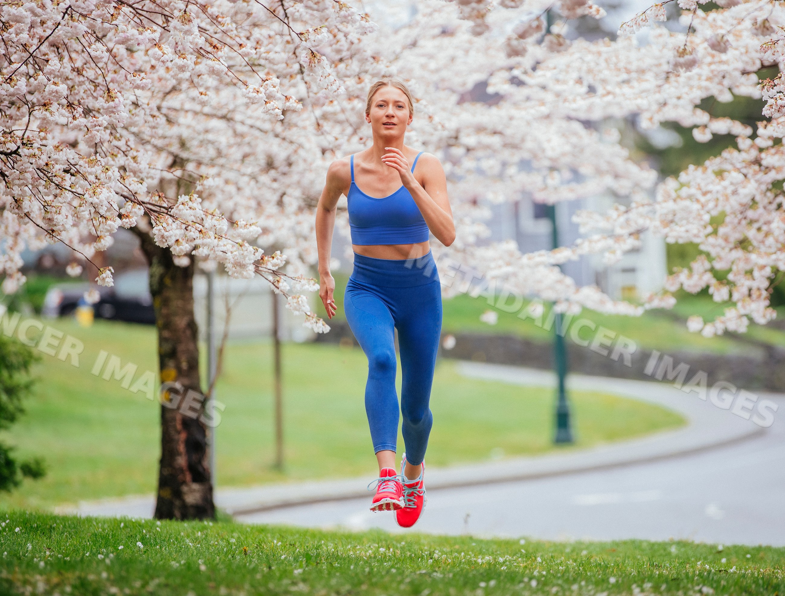 White woman running under cherry blossom trees in a park