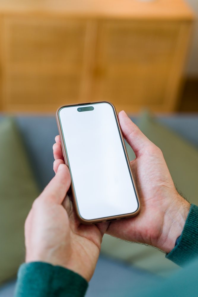 Smartphone with blank screen held in hands indoors