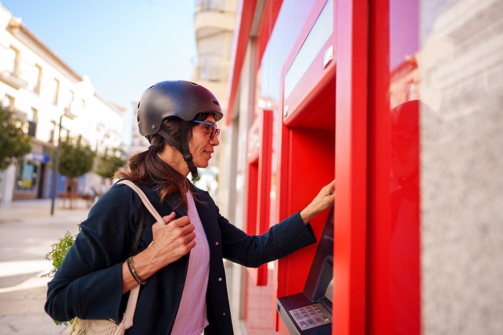 Hispanic woman using an atm on a street in a street