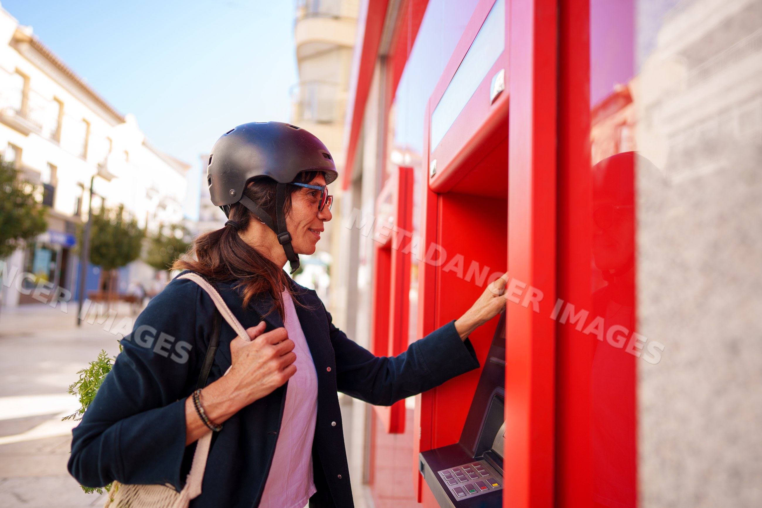 Hispanic woman using an atm on a street in a street