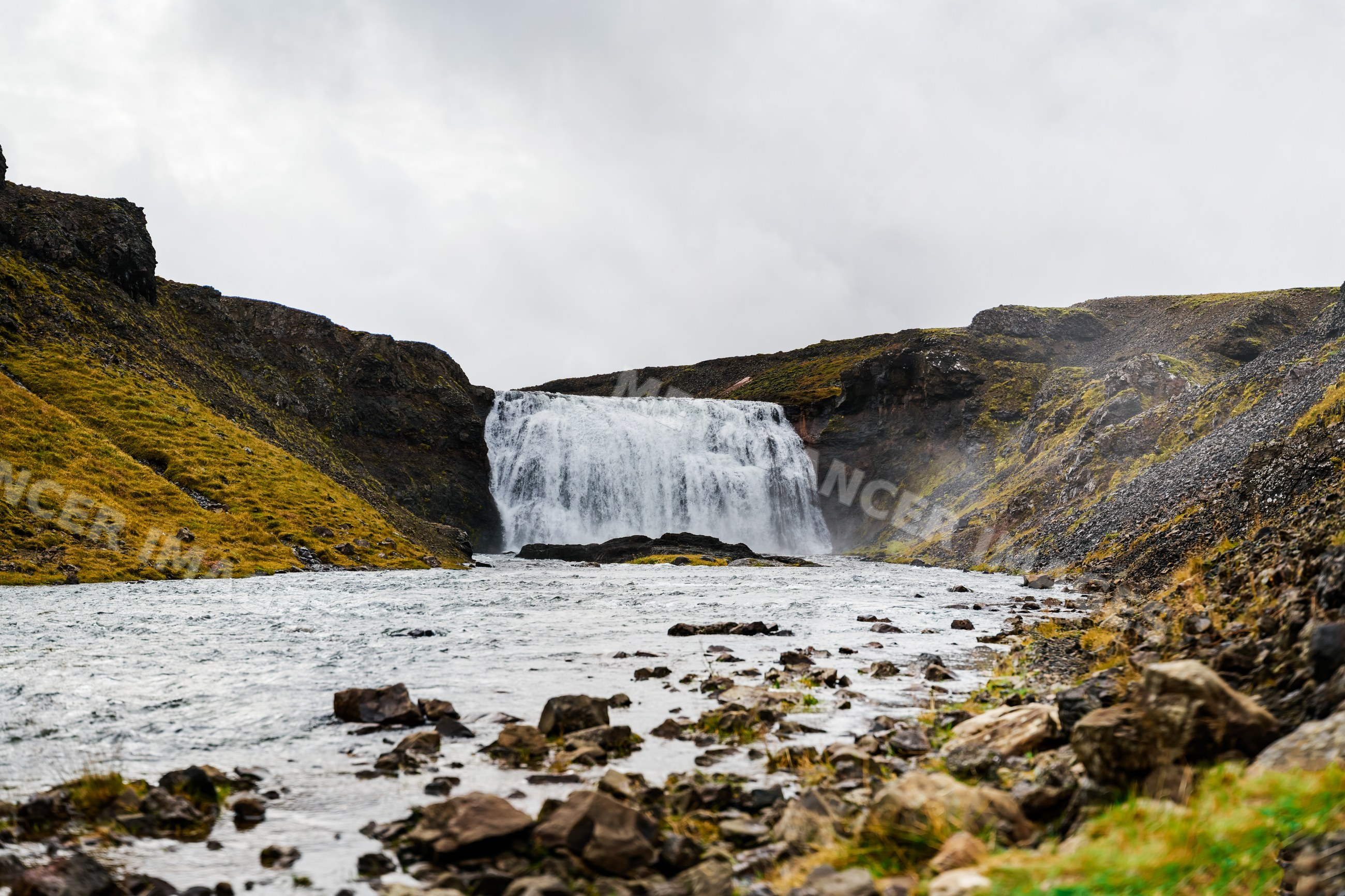Waterfall cascading into a rocky river in the landscape of Iceland