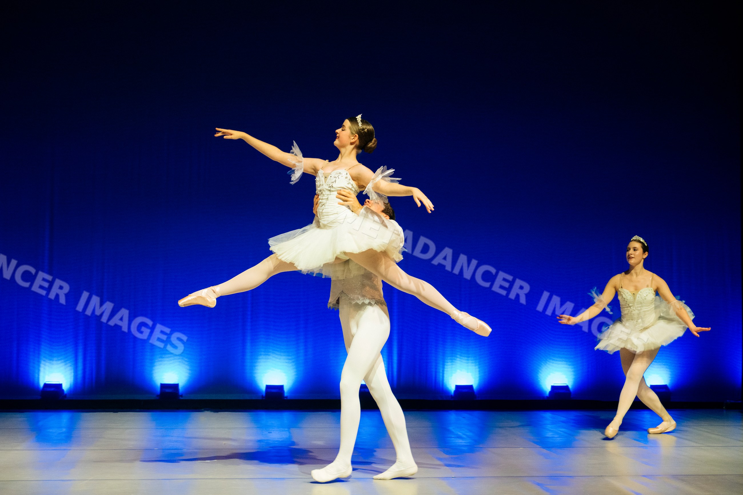 Ballet dancers perform a lift on stage during a holiday-themed dance