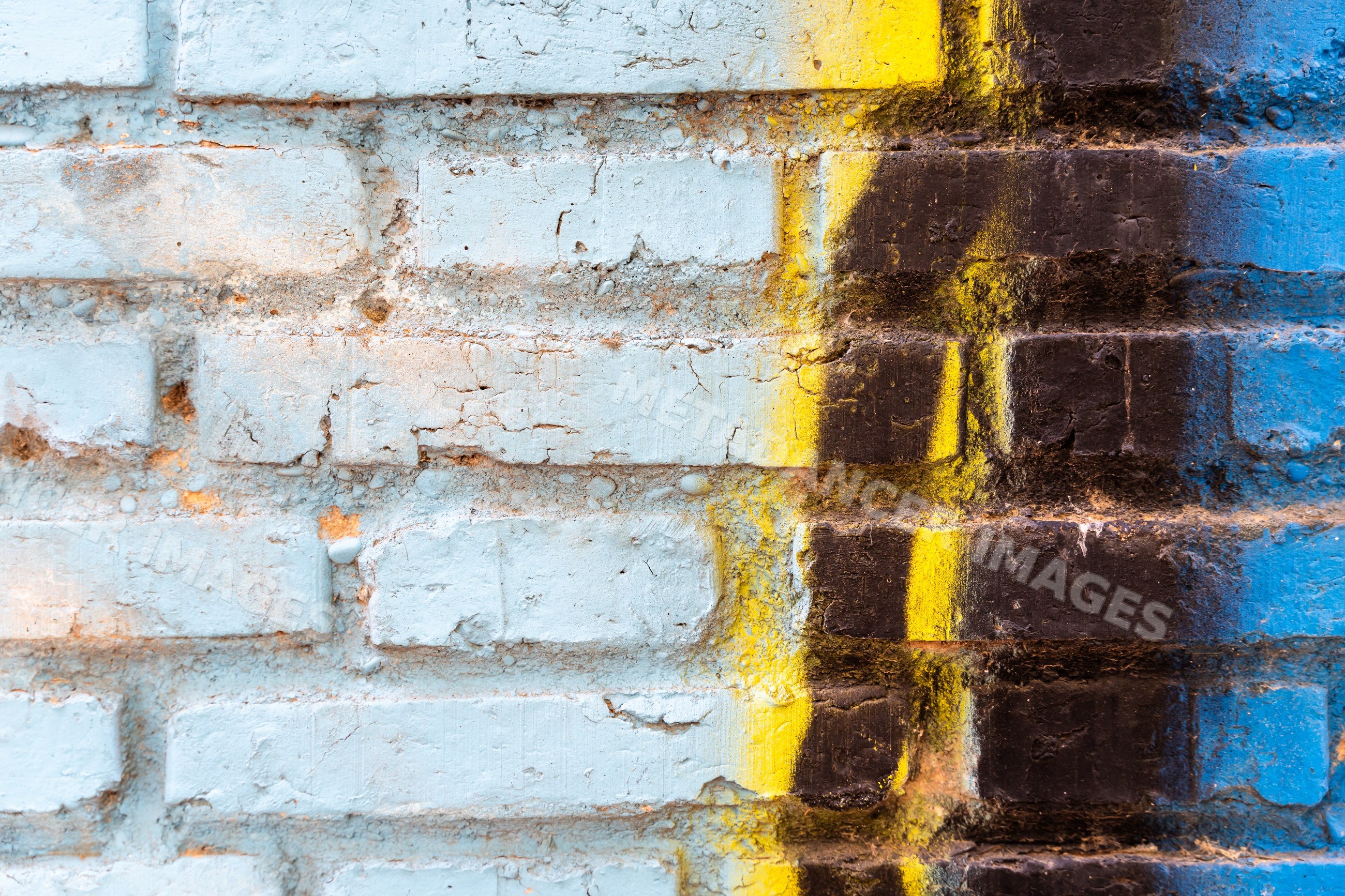 Painted brick wall with weathered blue, yellow